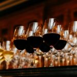 Many glasses filled with white and red wine on table. Dark colours. Wine collection